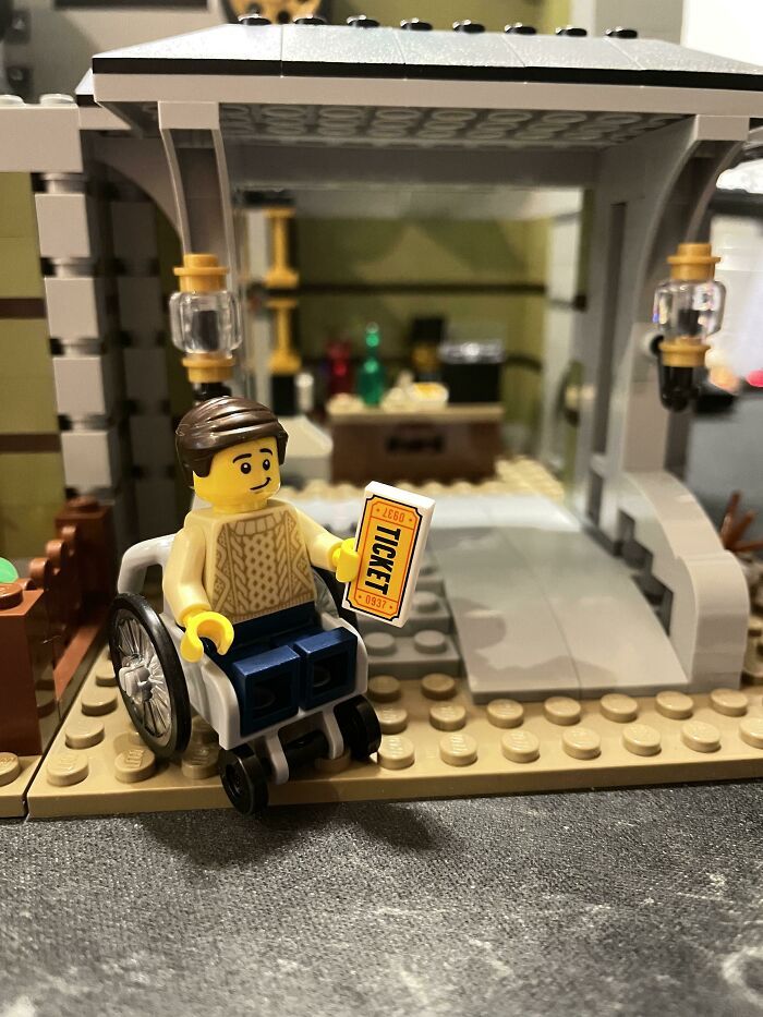 Le set lego comprend cette figurine/ce fauteuil roulant et intègre une rampe d’accès pour fauteuil roulant dans la construction.