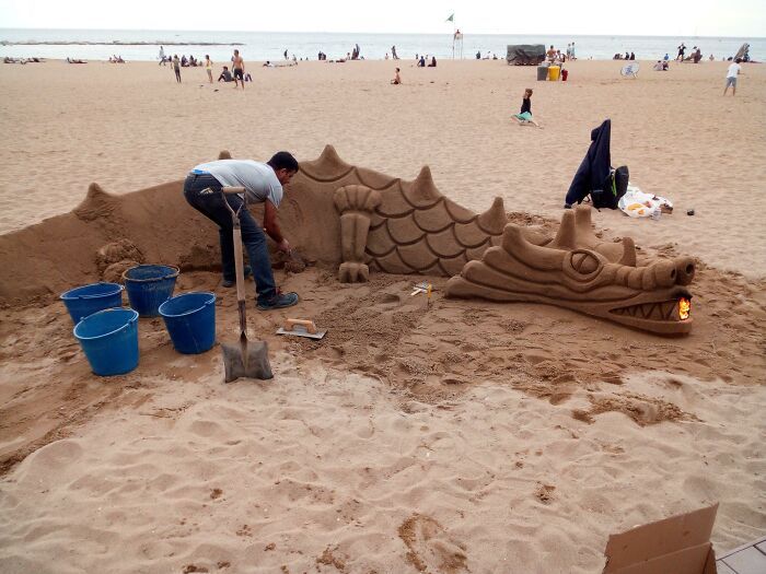 Sur une plage de Barcelone, ce type sculptait un dragon dans le sable, et il a mis un feu dans sa bouche pour faire croire qu’il crache du feu.