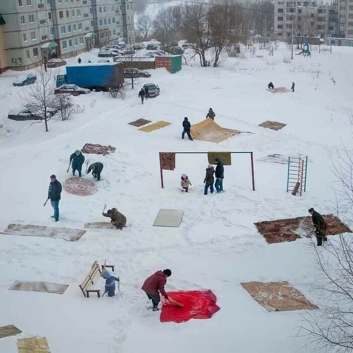 Des polissons nettoyant des tapis dans la neige