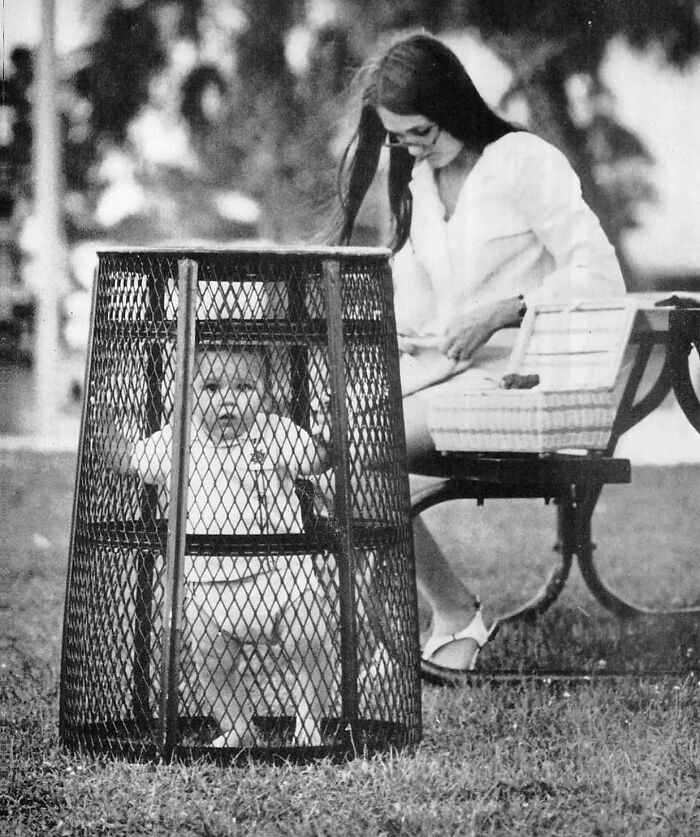 Une maman utilise une poubelle pour contenir son bébé pendant qu’elle fait du crochet dans le parc, 1969.