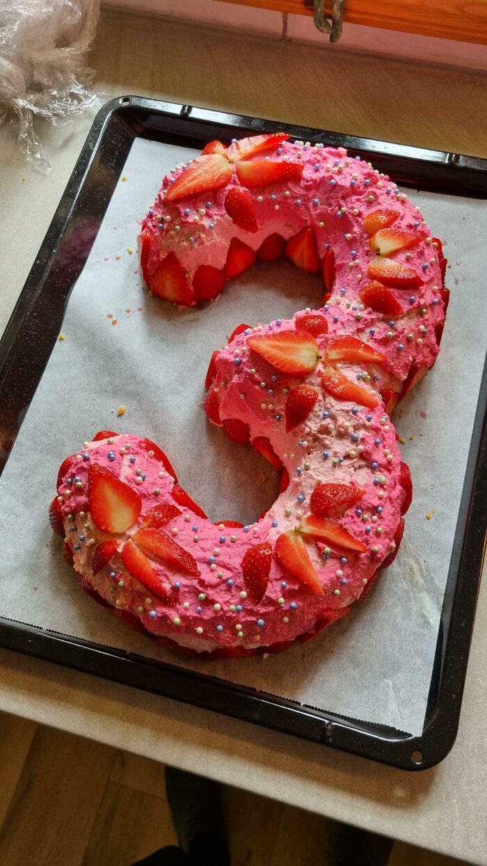 La fille voulait un gâteau d’anniversaire rose avec des fraises. La garniture est une crème anglaise et de la confiture de fraises.