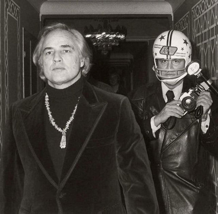 Le photographe paparazzi ron galella portait un casque de football autour de l’acteur marlon brando, après que brando l’ait frappé, lui ait cassé la mâchoire et fait sauter cinq dents en 1973.