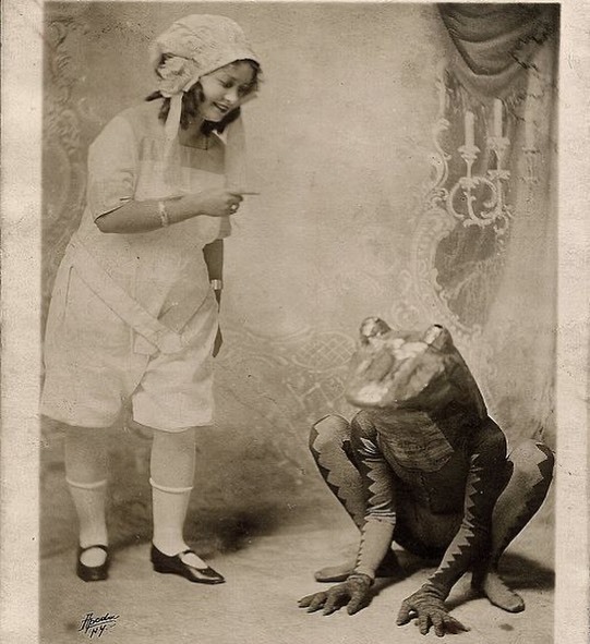Une jeune fille gronde une grenouille. Cette image étrange est une photo publicitaire de vaudeville réalisée par le studio Apeda de New York, vers 1920.