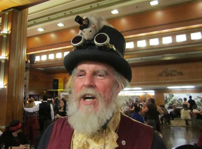 un vrai rat avec un chapeau haut de forme sur le haut du chapeau haut de forme de cet homme