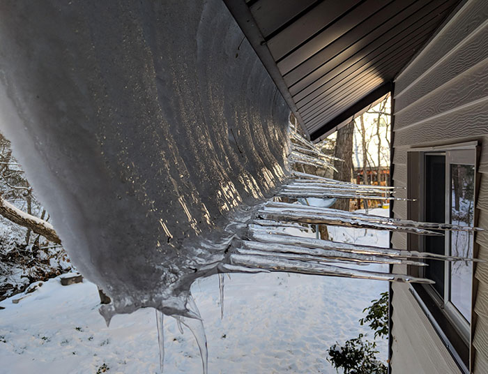 la neige a glissé du toit en partie avant de geler à nouveau, créant des glaçons horizontaux.