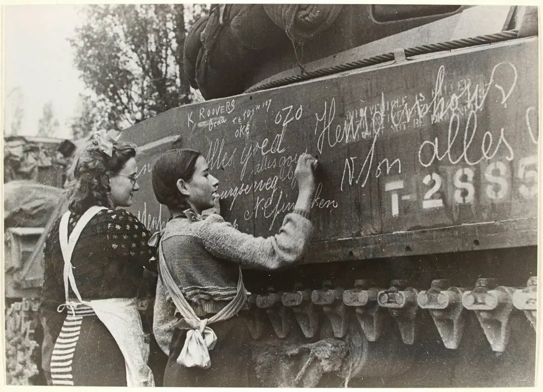 Dutch Girls Ria Vermeulen And Ineke Van Wijck Write Messages On A Polish Armoured Division Tank After The Liberation Of Breda, Their Hometown, Noord-Brabant Province, The Netherlands, 1944