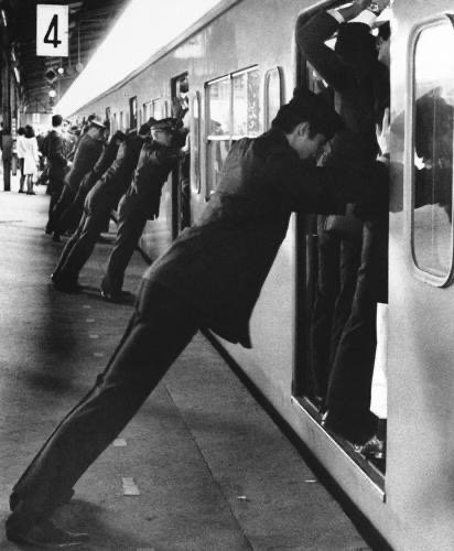 Les pousseurs du métro de Tokyo 1968 : les chefs de gare et le personnel de la gare poussent les passagers dans le train à l’heure de pointe à la station shinjiku de Tokyo.