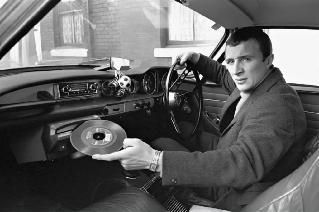 Mike Summerbee, joueur de Manchester City, fait une démonstration du tourne-disque intégré à sa nouvelle volvo p1800 (1967).
