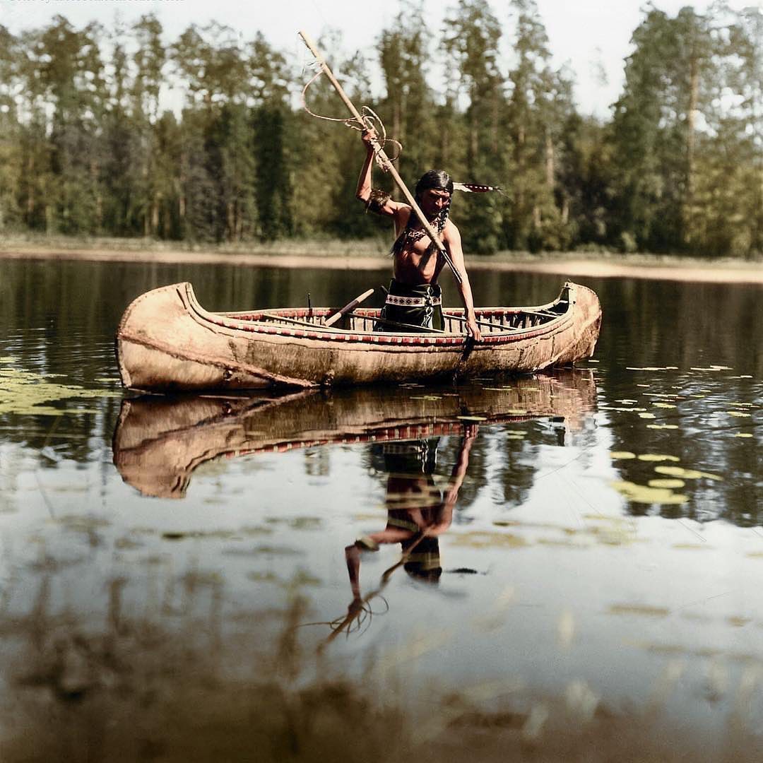 un amérindien, appartenant au peuple ojibwe, pêche au harpon dans un lac quelque part dans le minnesota, états-unis. photo prise en 1908