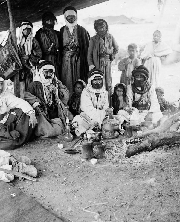 Hommes bédouins fumant une nargila (pipe à eau) dans leur camp du désert, vers 1900.