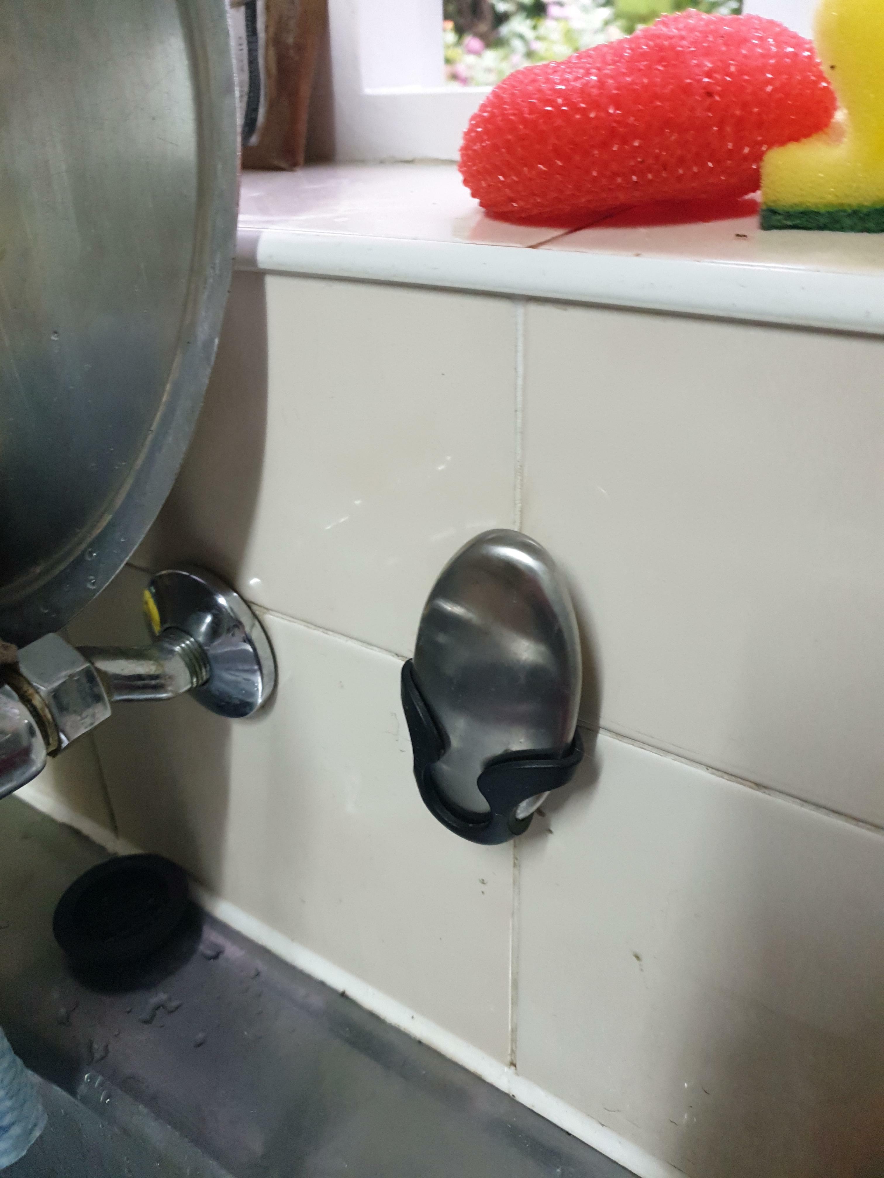 Qu'est-ce que ce truc métallique ovale dans un support en plastique fixé au mur de la cuisine à côté de l'évier ?