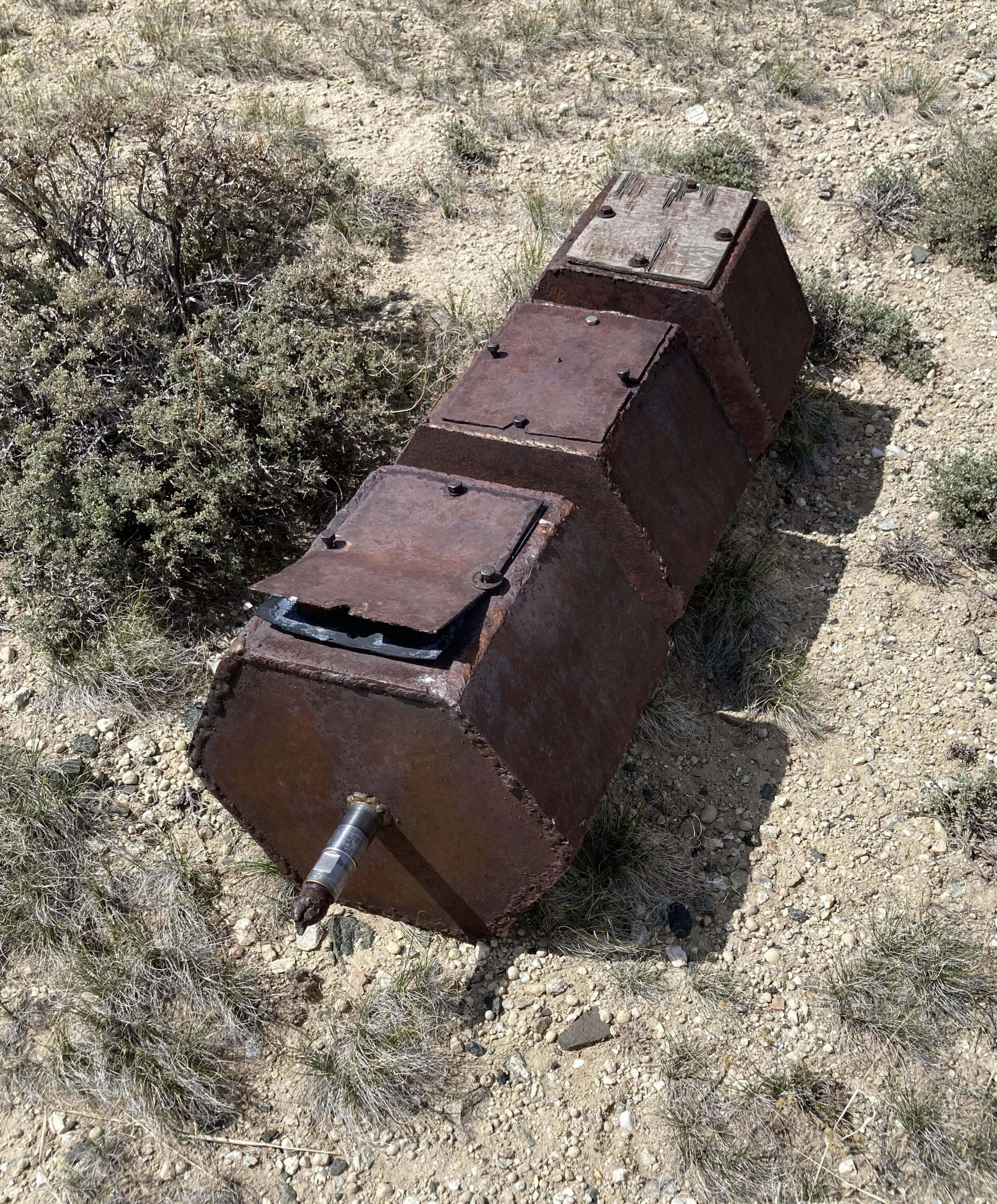 grand objet hexagonal en métal lourd trouvé dans le centre du wyoming. il comporte trois récipients évidés, chacun attaché à un tuyau central. les 