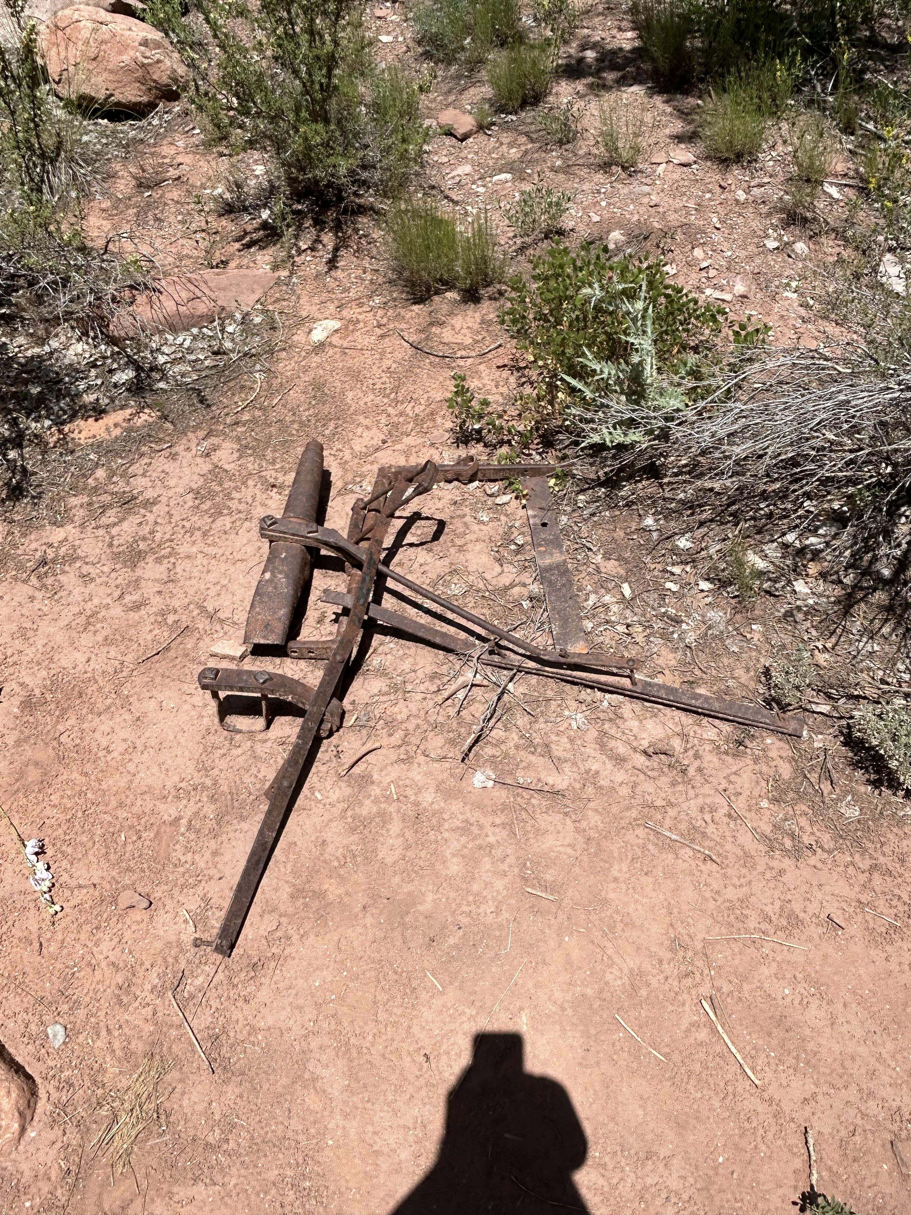 engin trouvé sur un sentier de randonnée dans l'utah composé de plusieurs pièces de métal plates et rondes, maintenues ensemble par des vis avec une partie creuse plus épaisse parallèle à la bande de métal la plus longue.