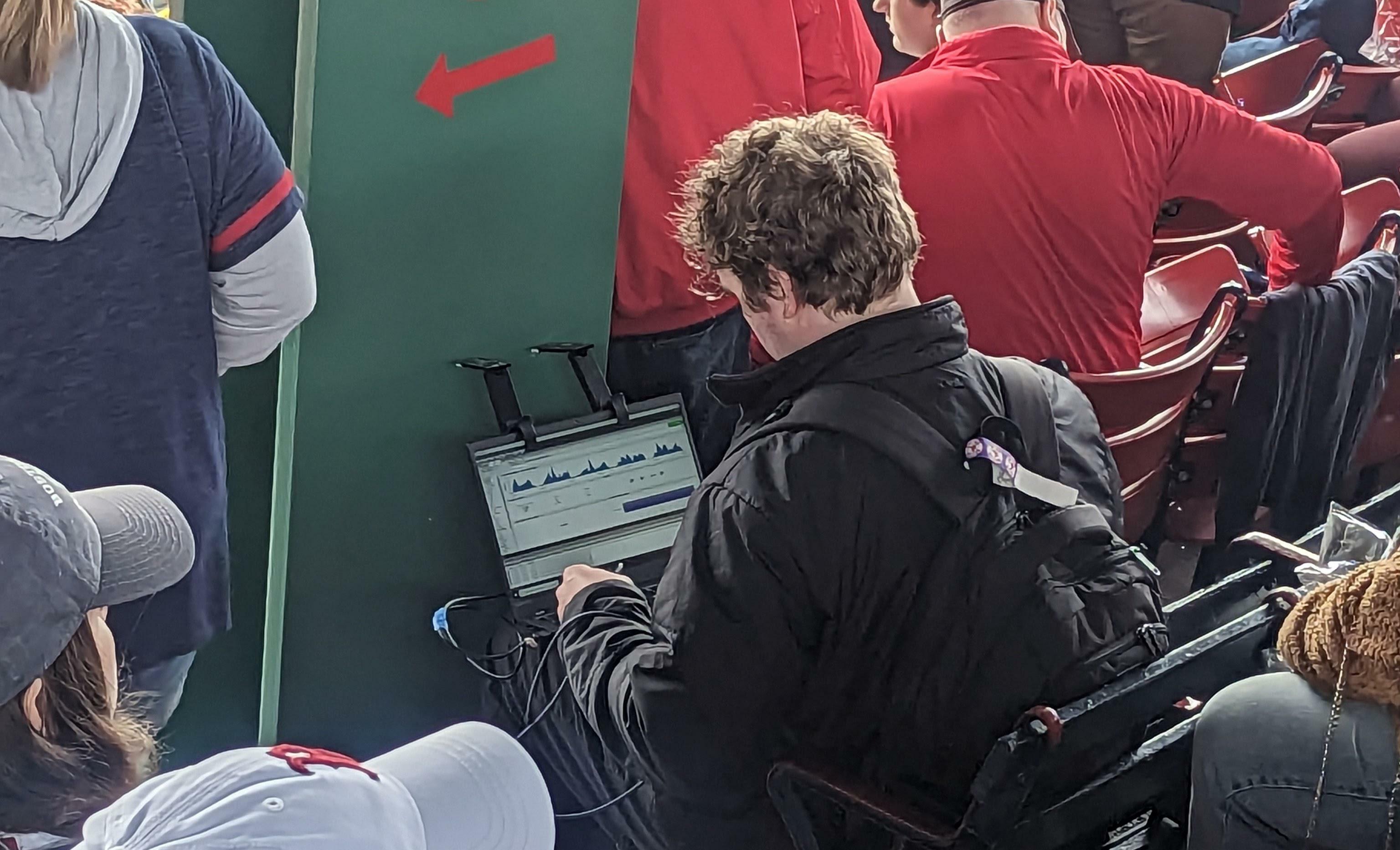 Un ordinateur portable avec des capteurs pliables et des fils allant dans un sac à dos. Ils semblent mesurer quelque chose. J'ai vu plusieurs personnes se promener avec ces installations lors d'un match de baseball de la ligue majeure.