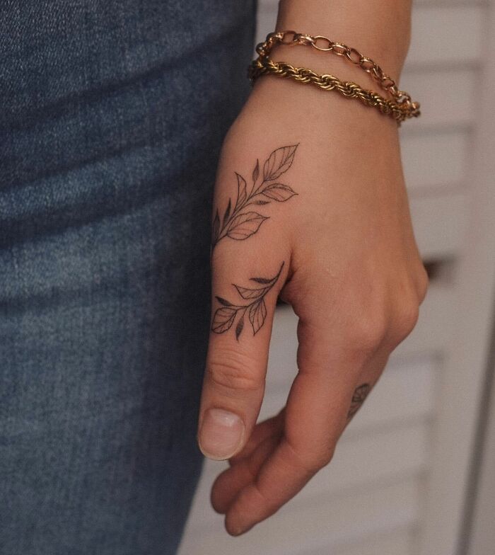 tatouage de vignes enveloppant le pouce et la main