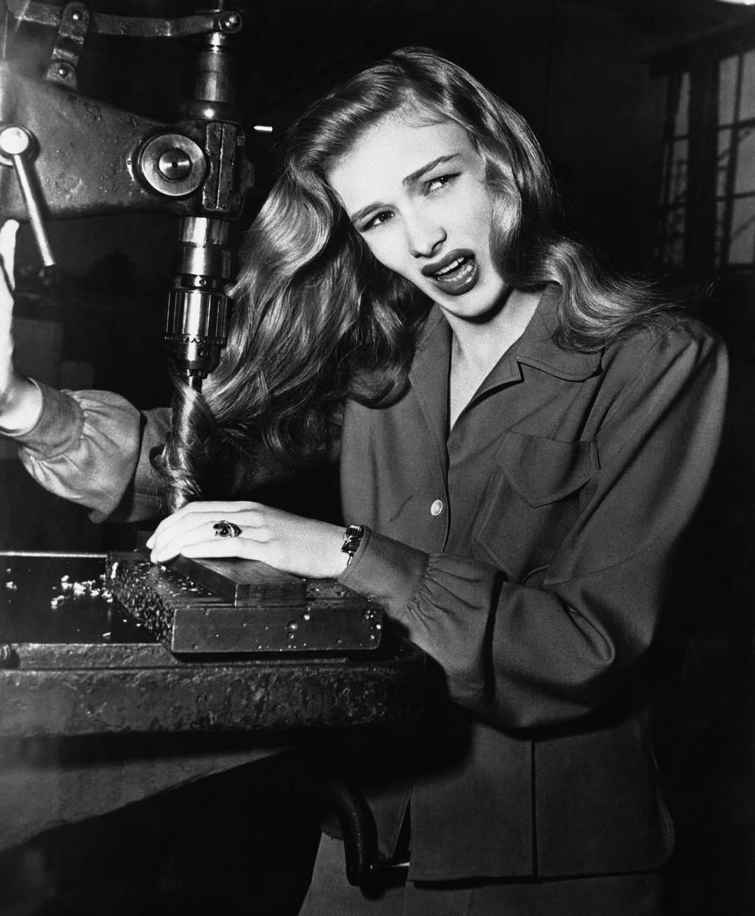 L’actrice Veronica Lake avec ses cheveux tordus dans une perceuse à colonne, démontrant les dangers potentiels pour les femmes dans les usines pendant la Seconde Guerre mondiale. Novembre 1943